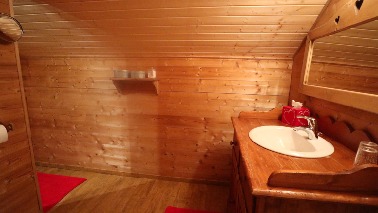 Salle de bain en bois ouverte sur une autre pice, lavabo avec miroir et wc