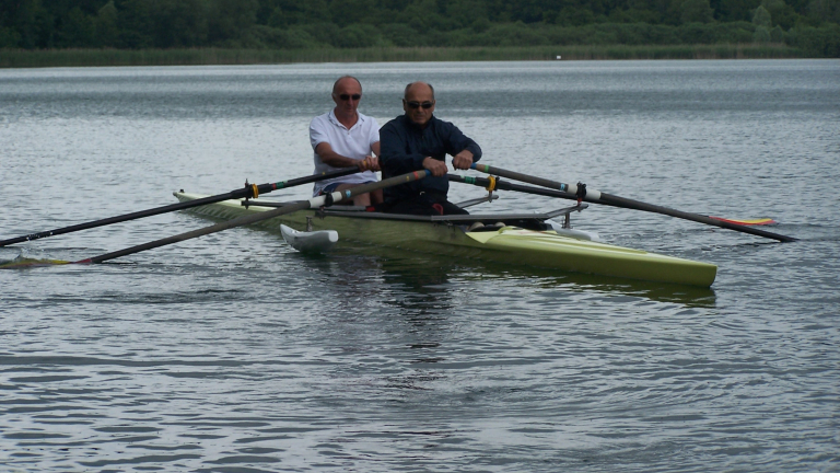  bord d'un aviron stabilis sur l'eau, deux personnes rament sur le lac. L'aviron est adapt  l'accueil de deux personnes en situation de handicap.