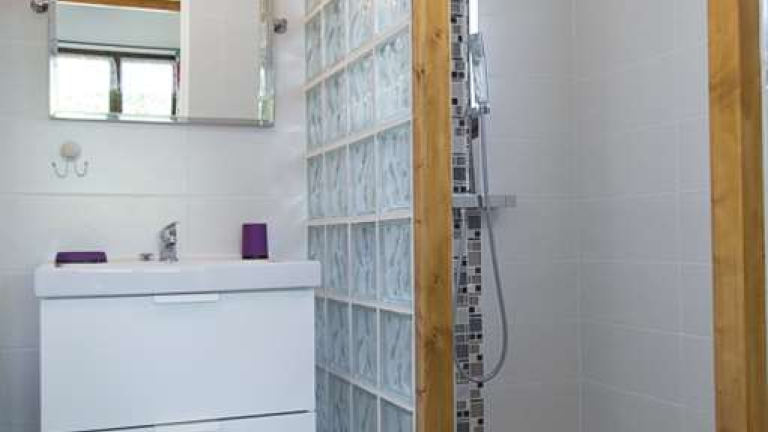 Salle de bain dans les tons clairs avec Douche  l'italienne avec mosaiques et vasque avec placard sous vier et miroir