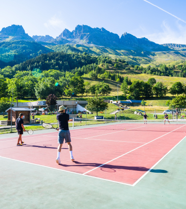 Terrain de tennis au soleil face aux montagnes.