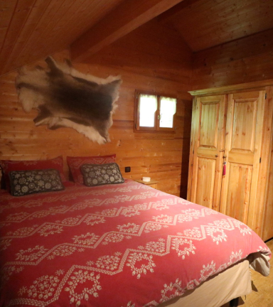 Chambre en bois, grande armoire de rangement en bois  ct du lit double, peau de bte accroche au mur au dessus de la tte de lit