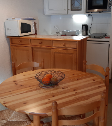Coin cuisine, table ronde en bois, 4 chaises, micro-ondes, four, frigo, plaques lctriques et placard de rangement