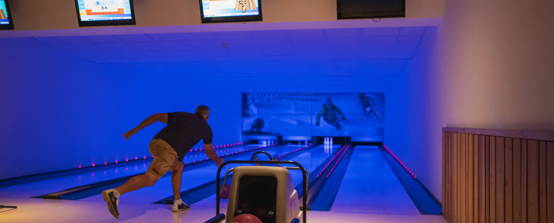 Homme qui lance sa boule de bowling sur la piste.