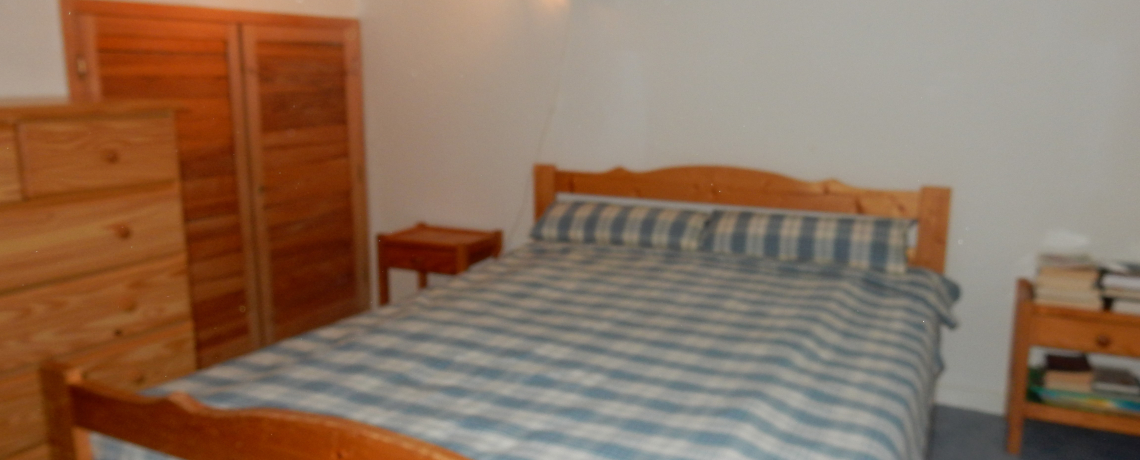 Chambre avec un lit double, armoire et commode ainsi que deux tables de nuit