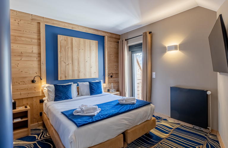 Chambre en bois et peinture bleue et moquette bleue et beige.