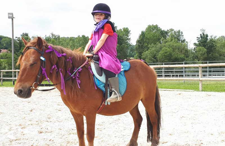 Une enfant installe sur un poney et parfaitement quipe s'apprte  faire un tour de piste avec lui